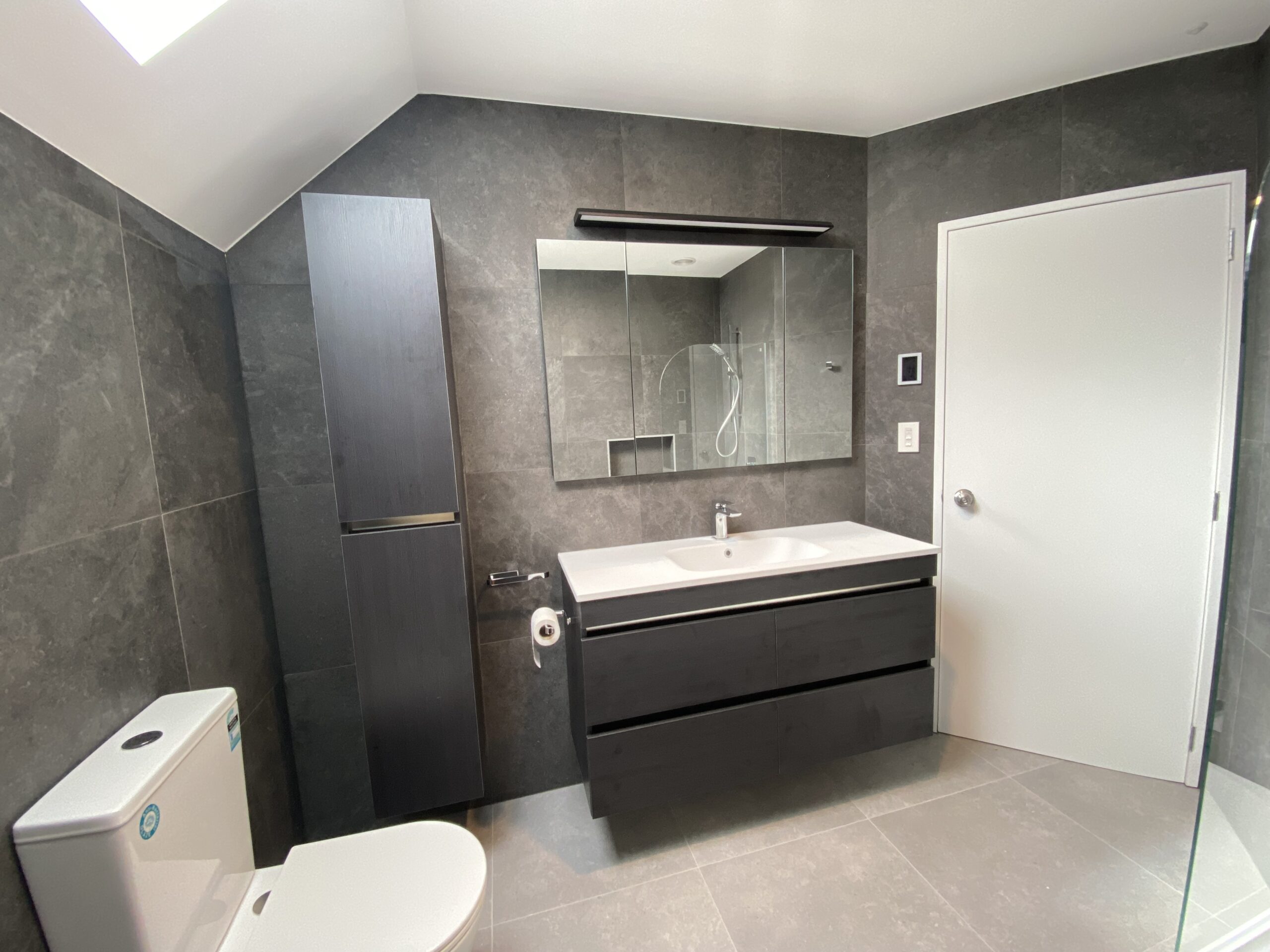 A finished bathroom with grey tiles and a wall-hung vanity