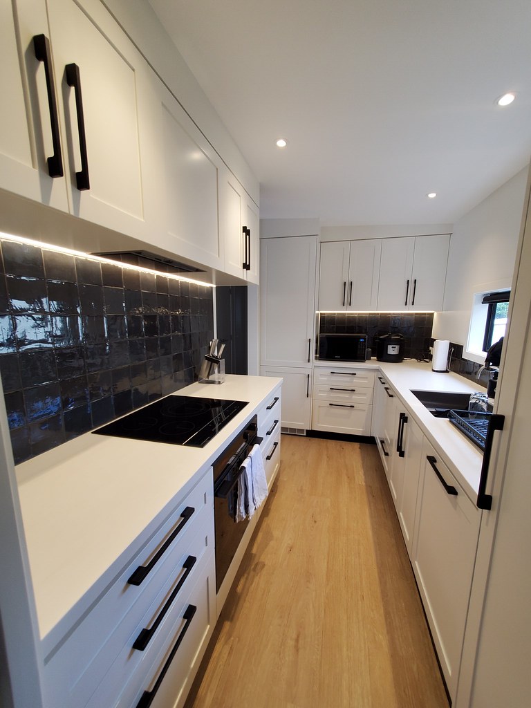 A renovated kitchen with white cabinets and black tiles